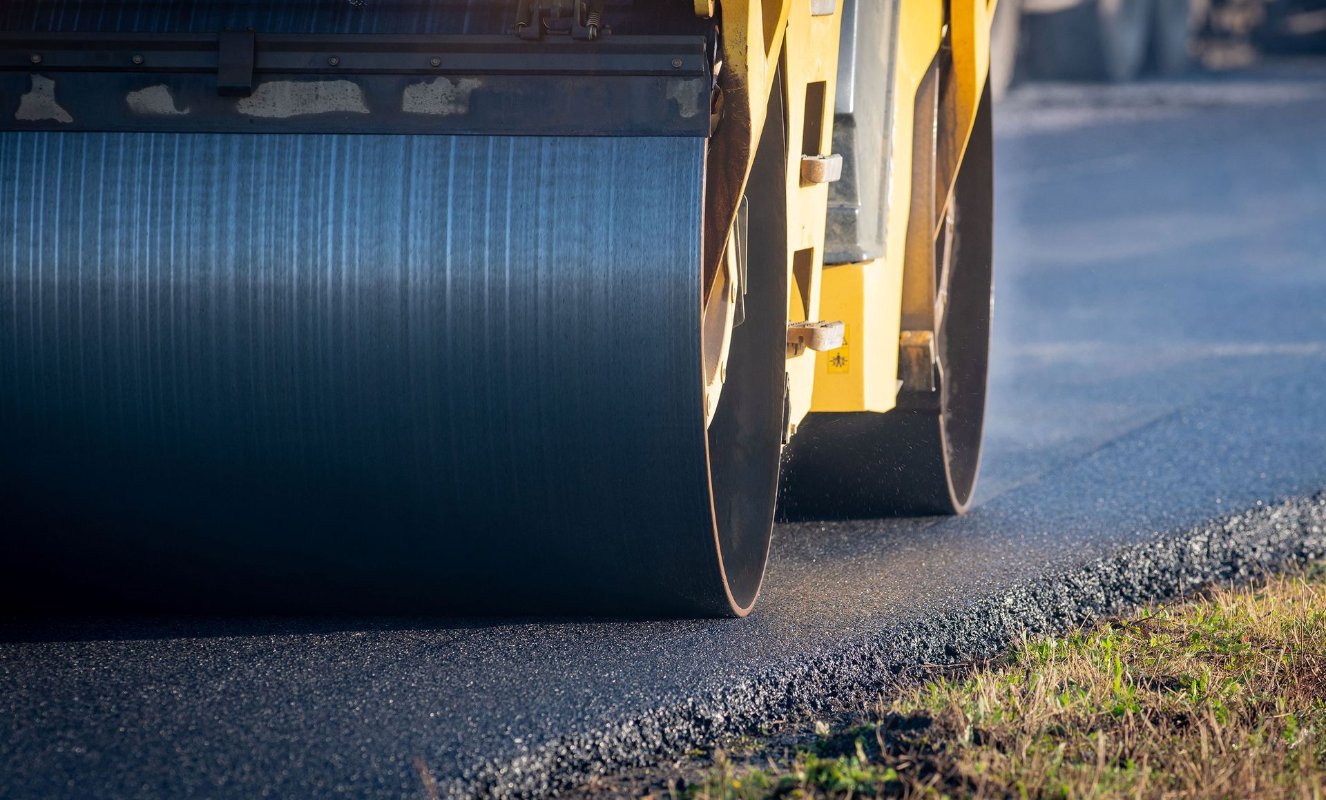 Heavy roller compacting fresh asphalt on a paving job